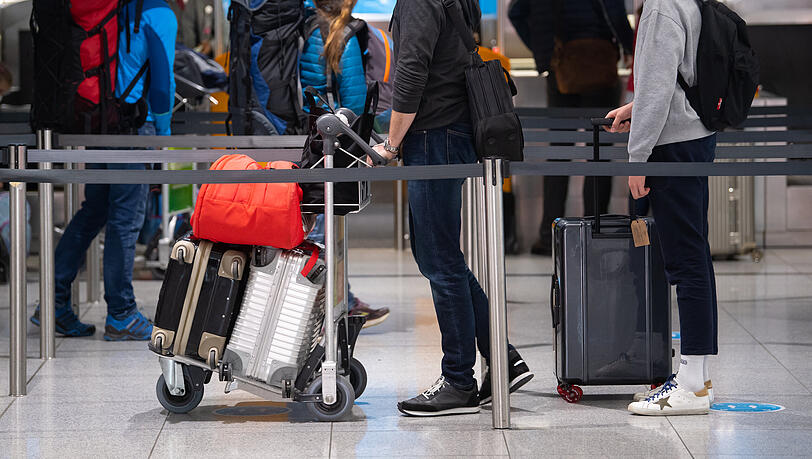 Reisende stehen am Flughafen München mit ihren Koffern am Check-In Schalter. Reisende stehen am Flughafen München mit ihren Koffern am Check-In Schalter.