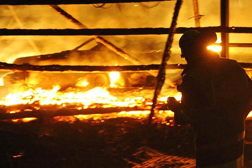 Flammenhölle in Aying: Auf einem Bauernhof ist eine Lagerhalle mit teuren Oldtimern abgebrannt. Auf dem Bild sind schemenaft in den Flammen die Umrisse eines Wagen zu erkennen...