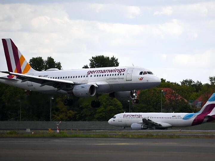 Ein Flugzeug der Airline Germanwings landet auf dem Flughafen Tegel, während im Hintergrund ein Flugzeug der Airline Eurowings auf dem Rollfeld steht. Foto: Monika Skolimowska/zb/dpa/Archivbild