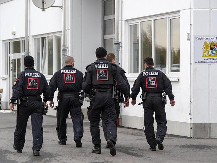 Polizisten gehen auf dem Gelände der Außenstelle Stephansposching des Ankerzentrums Deggendorf. Foto: Armin Weigel/Archiv