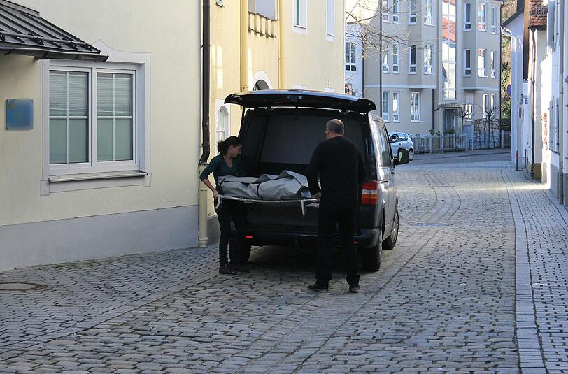 Bestatter tragen die Leiche des ermordeten Mitbewohners aus dem Haus.