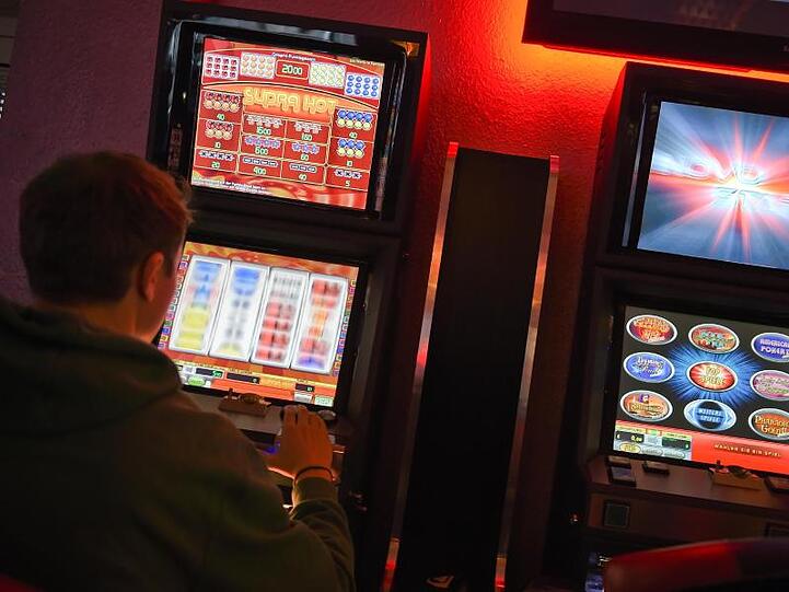 Ein junger Mann spielt an einem Spielautomaten.