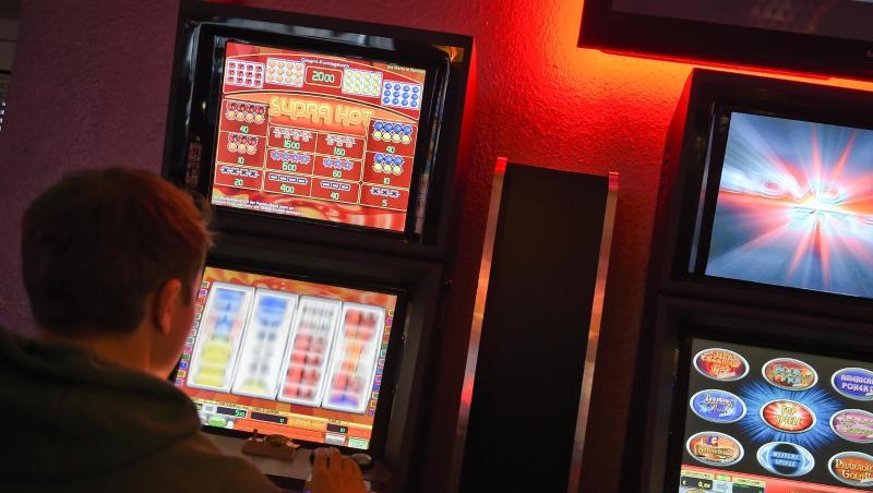 Ein junger Mann spielt an einem Spielautomaten. Ein junger Mann spielt an einem Spielautomaten.