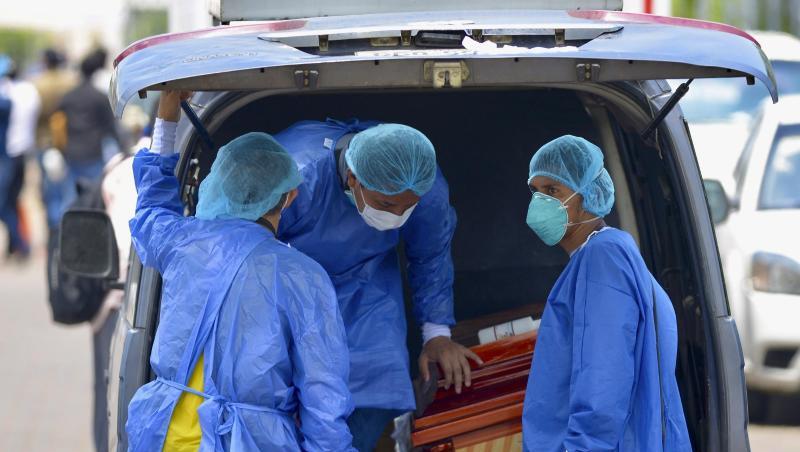 Männer mit Schutzanzügen laden in der Hafenstadt Guayaquil in Ecuador einen Sarg in einen Wagen vor einem Krankenhaus. Männer mit Schutzanzügen laden in der Hafenstadt Guayaquil in Ecuador einen Sarg in einen Wagen vor einem Krankenhaus.