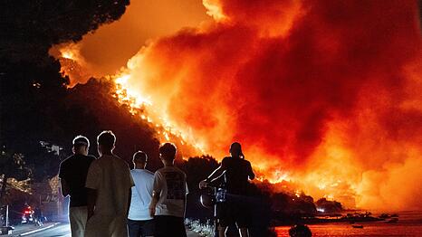 Menschen beobachten am fr&uuml;hen Freitag, dem 14. August 2026, einen Waldbrand an der Adriak&uuml;ste in der N&auml;he von Omis im S&uuml;den Kroatiens.