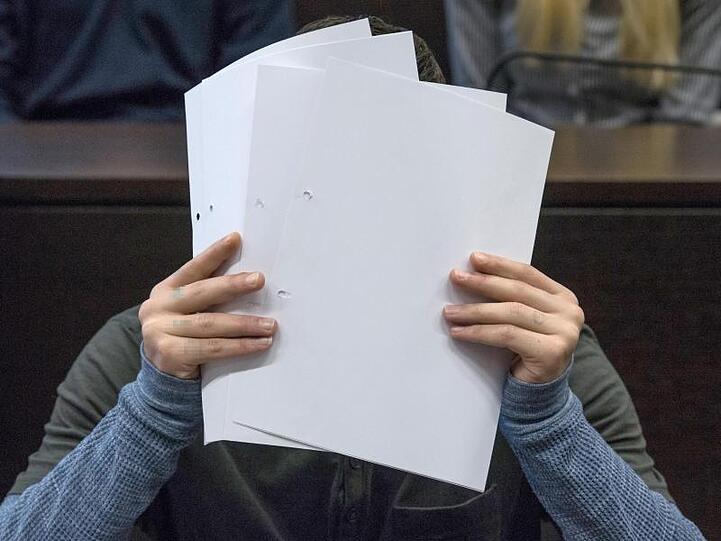 Mit Zetteln verdeckt Ali B. beim Betreten des Gerichtssaals sein Gesicht vor den Kameras der Journalisten.