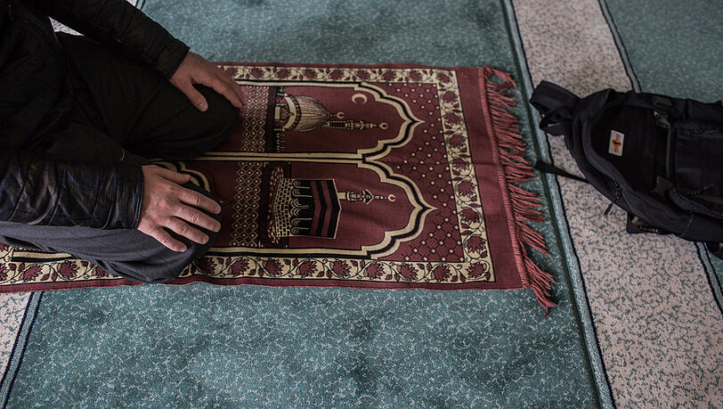 Ein Muslim kniet w&auml;hrend eines Gebets auf einem Gebetsteppich.