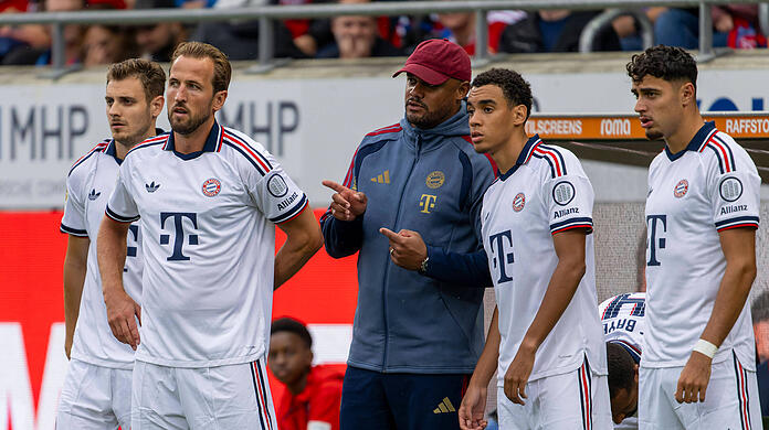Bayern-Trainer Vincent Kompany (3.v.l.) vor der Einwechslung im Gespr&auml;ch mit Jamal Musiala (2.v.r.). Ebenfalls dabei: Josip Stanisic (l.), Harry Kane (2.v.l.) und Aleksandar Pavlović (r.).