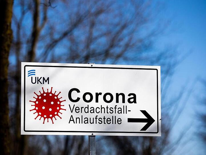 Ein Hinweisschild mit der Aufschrift "Corona Verdachtsfall-Anlaufstelle" steht vor der Uniklinik Münster.