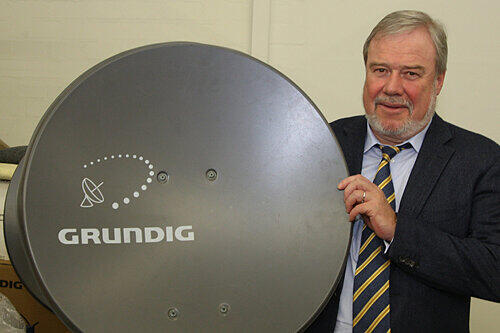 GSS-Chef Fred Hübner mit einer Satelliten-Schüssel, die das Zeichen seiner Firma trägt. Normalerweise sind die GSS-Anlagen aber größer.