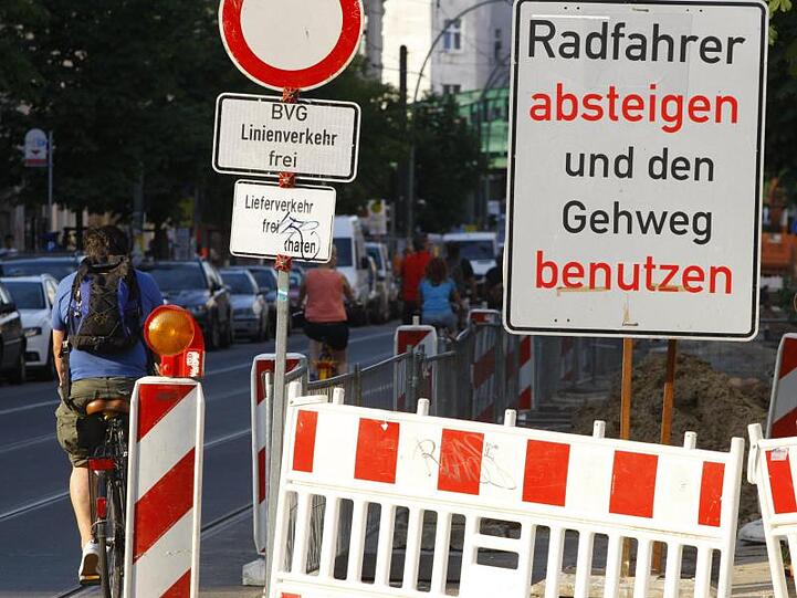 Wird in Berlin eher als freundliche Empfehlung interpretiert: Radfahrer fahren in der Kastanienallee verbotenerweise an einem Schild mit der Aufschrift "Radfahrer absteigen und den Gehweg benutzen" vorbei.