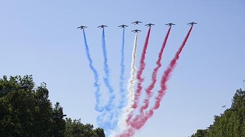 Jets der Patrouille de France fliegen über den Arc de Triumph und die Champs Elysees.