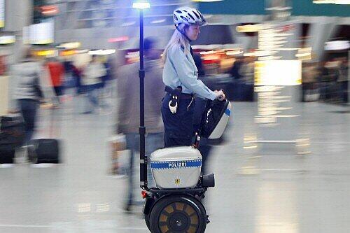 Polizistin mit Steh-Elektroroller auf dem Düsseldorfer Flughafen
