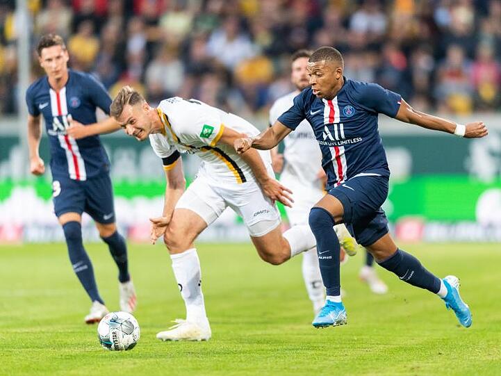 PSG-Star Pariser Kylian Mbappe (r) verfolgt Dynamos Florian Ballas, Julian Draxler (l) schaut zu.
