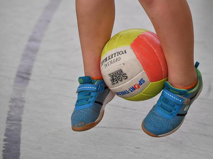 Ein Schulkind hüpft mit einem Ball zwischen den Beinen.