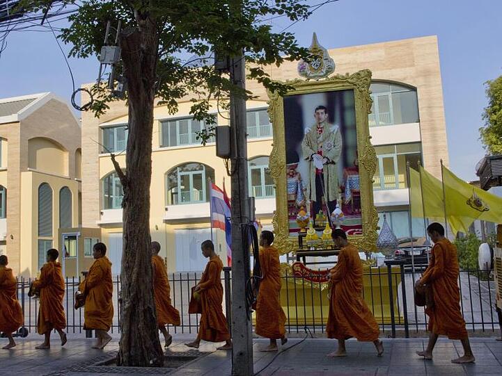 Buddhistische Mönche ziehen an einem Porträt von Thailands neuen König vorbei.