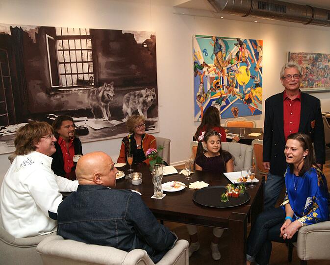 Uli Richter (stehend) mit Gästen bei der Eröffnungsparty Anfang Juli
&ndash; an der Wand die Bilder, die derzeit in der Galerie ausgestellt sind.