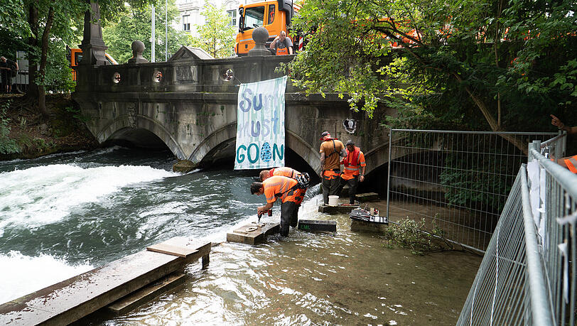 Betonklötze und Absperrungen werden am Eisbach entfernt. Im Hintergrund ist ein Banner mit der Aufschrift «Surf must go on» an der Eisbachbrücke an der Eisbachwelle befestigt. Seit dem Tod einer Surferin im Münchner Eisbach war die Welle gesperrt. Die Ermittlungen sind beendet - und jetzt auch die Wartezeit für die Wellenreiter. Doch für sie gibt es neue Regeln. Betonklötze und Absperrungen werden am Eisbach entfernt. Im Hintergrund ist ein Banner mit der Aufschrift «Surf must go on» an der Eisbachbrücke an der Eisbachwelle befestigt. Seit dem Tod einer Surferin im Münchner Eisbach war die Welle gesperrt. Die Ermittlungen sind beendet - und jetzt auch die Wartezeit für die Wellenreiter. Doch für sie gibt es neue Regeln.