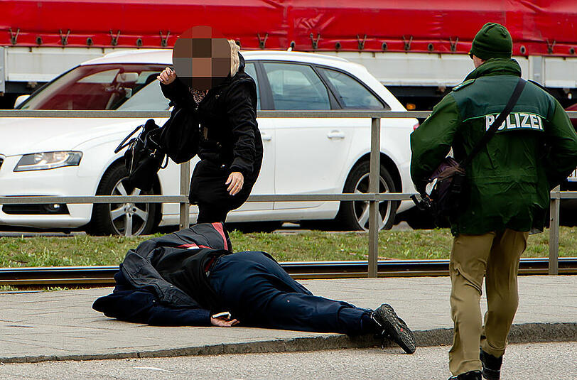 Eine Polizist eilt einem gestürzten Mann zur Hilfe...