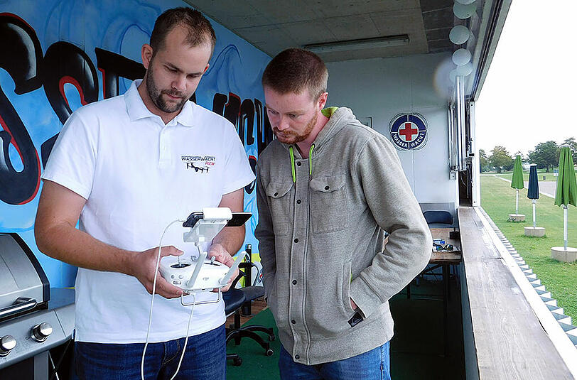 Markus Schmirler von der Wasserwacht (l.) und Student Thomas Fuchs beobachten auf dem Smartphone, was die Drohnenkamera aufnimmt.