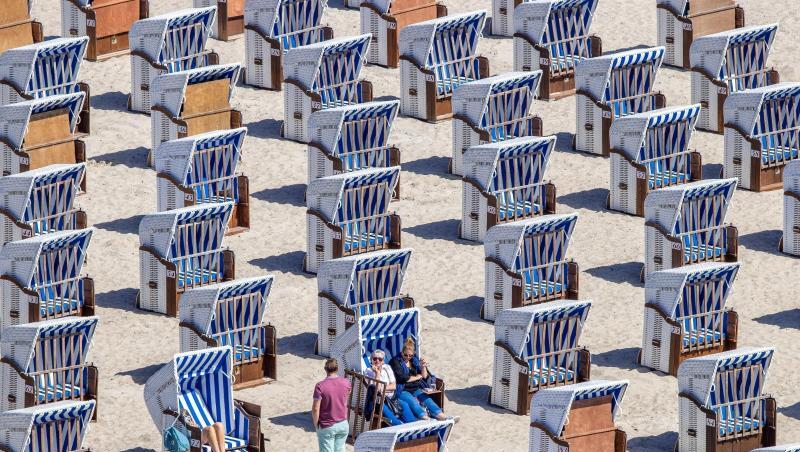 Erste Urlauber sitzen in Strandkörben am Ostseestrand in Warnemünde. Erste Urlauber sitzen in Strandkörben am Ostseestrand in Warnemünde.