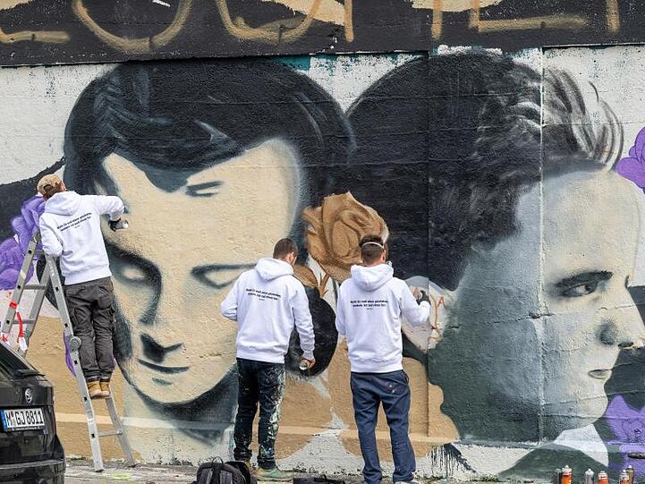 Drei Männer arbeiten an einem Graffito mit dem Bildnis von Hans Scholl. Foto: Peter Kneffel/dpa