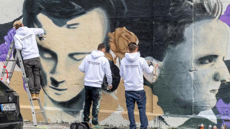 Drei Männer arbeiten an einem Graffito mit dem Bildnis von Hans Scholl. Foto: Peter Kneffel/dpa Drei Männer arbeiten an einem Graffito mit dem Bildnis von Hans Scholl. Foto: Peter Kneffel/dpa