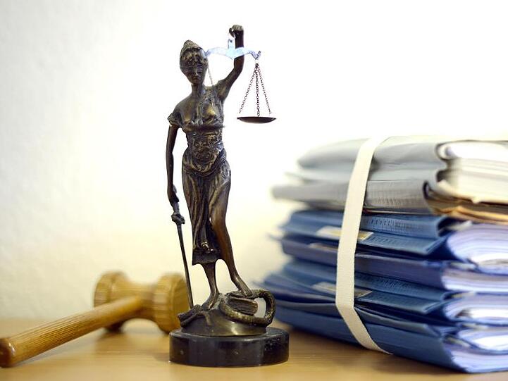 Justitia mit Holzhammer und Aktenstapel. Foto: Volker Hartmann/dpa/Symbolbild