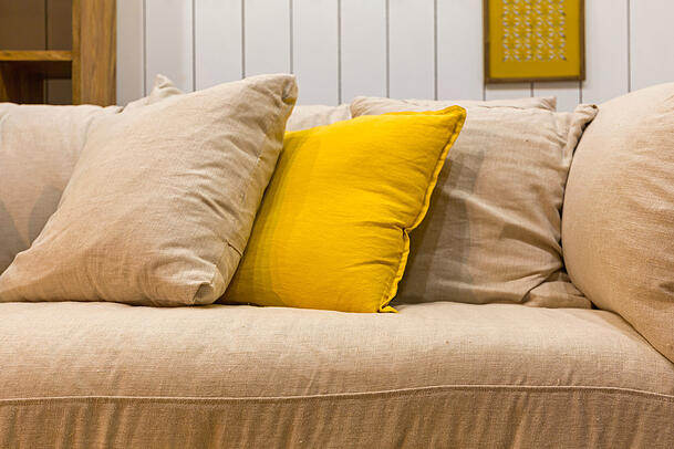 Viele Kissen auf der Couch sehen zwar schön aus, sind aber große Staubfänger. (Symbolbild)