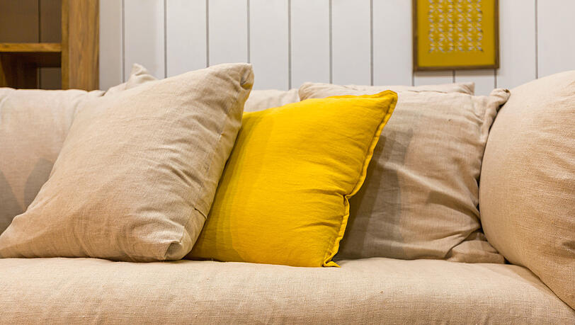 Viele Kissen auf der Couch sehen zwar schön aus, sind aber große Staubfänger. (Symbolbild) Viele Kissen auf der Couch sehen zwar schön aus, sind aber große Staubfänger. (Symbolbild)