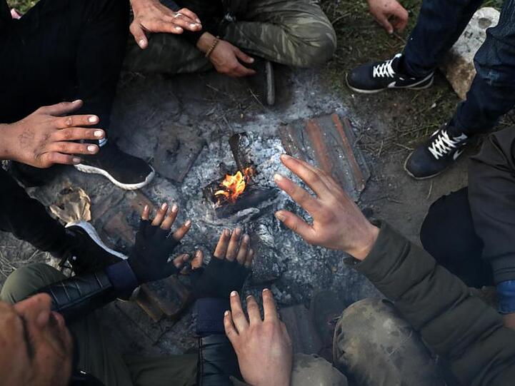 Migranten sitzen nahe der türkisch-griechischen Grenze um ein Lagerfeuer herum und versuchen, sich zu wärmen.