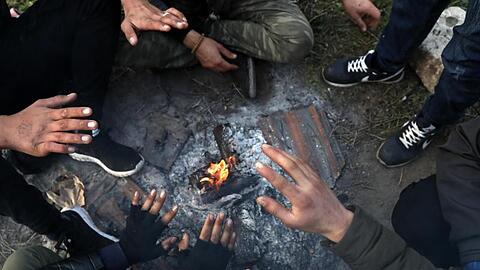 Migranten sitzen nahe der türkisch-griechischen Grenze um ein Lagerfeuer herum und versuchen, sich zu wärmen.