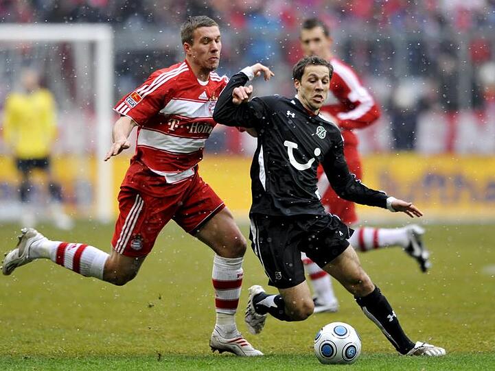 Lukas Podolski (l) und Steven Cherundolo von Hannover 96 kämpfen um den Ball.