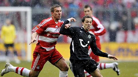 Lukas Podolski (l) und Steven Cherundolo von Hannover 96 kämpfen um den Ball.