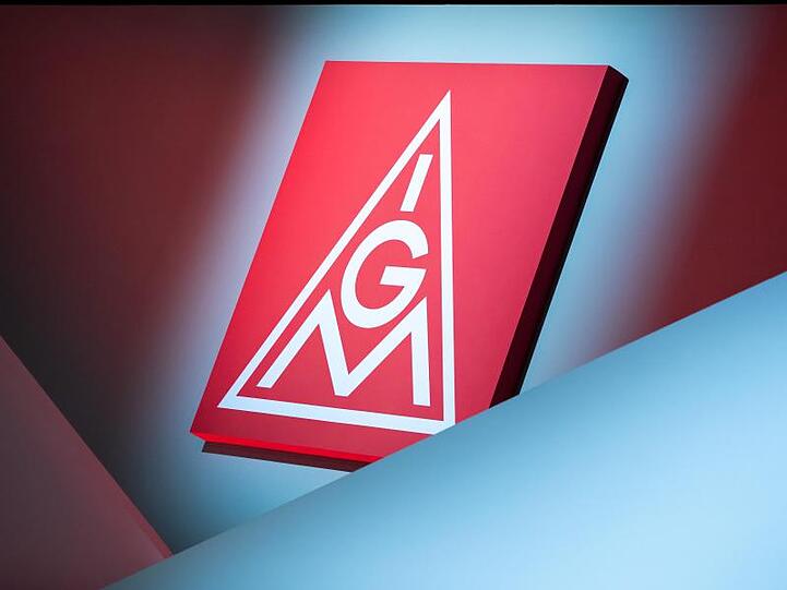 Das Logo der IG Metall hängt über einer Bühne. Foto: Daniel Karmann/dpa/Symbolbild