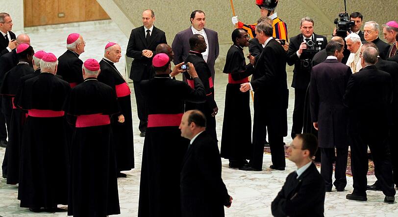 Benedikts Kardinäle begrüßen den Papst umringt von zahlreichen Medienvertretern in der Audienzhalle Paolo VI im Vatikan. Es ist das erste Mal, dass sich der Pontifex nach seiner historischen Rücktrittankündigung vom Montag den Gläubigen zeigt. Die Bilder.