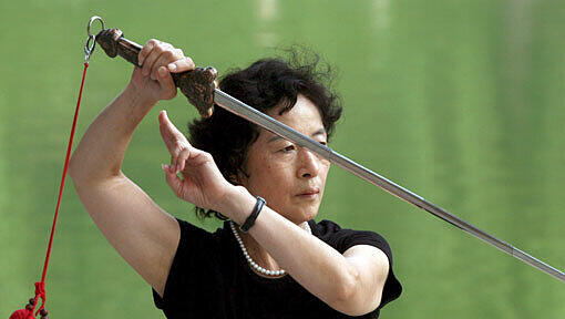Eine Frau bei einer traditionellen Tai-Chi-Übung mit Schwert (Symbolbild) Eine Frau bei einer traditionellen Tai-Chi-Übung mit Schwert (Symbolbild)