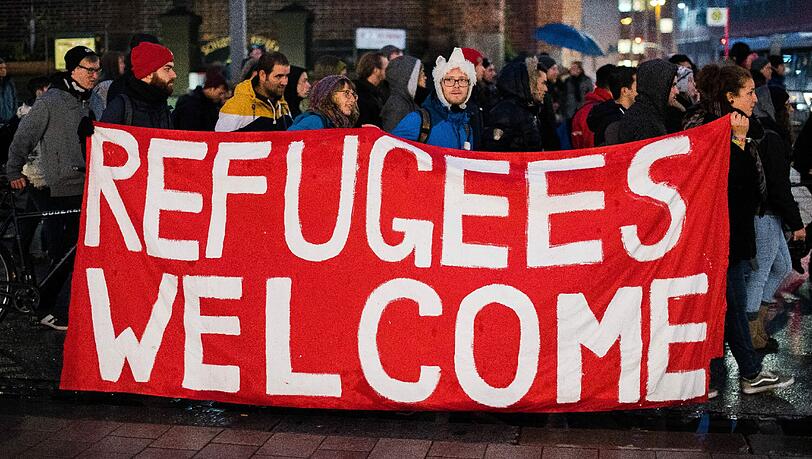 Teilnehmer einer Demonstration gegen die Verschärfung des Asylrechts halten in der Innenstadt in Hamburg ein Banner mit der Aufschrift "Refugees welcome".