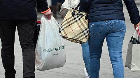 Menschen tragen in einer Einkaufsstraße Taschen und Tüten.