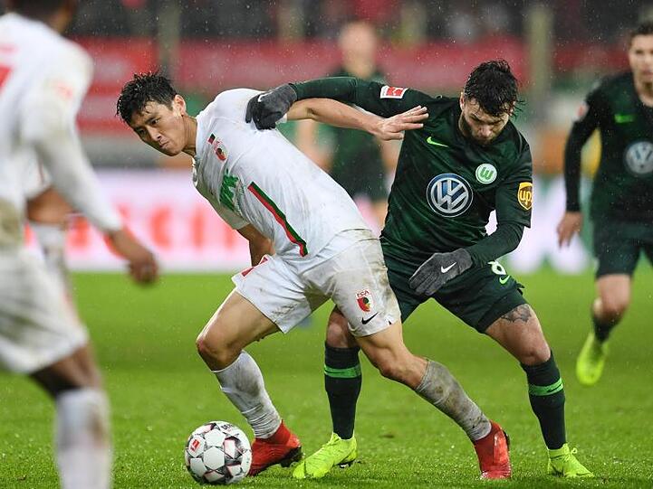 Ja-Cheol Koo (l) von Augsburg und Renato Steffen von Wolfsburg kämpfen um den Ball. Foto: Tobias Hase/Archiv