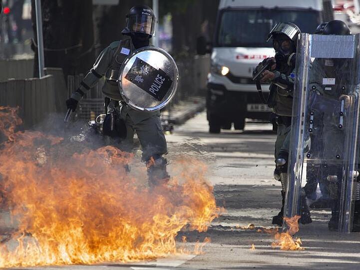 Ein Molotow-Cocktail geht vor Polizisten in Flammen auf.