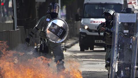 Ein Molotow-Cocktail geht vor Polizisten in Flammen auf.