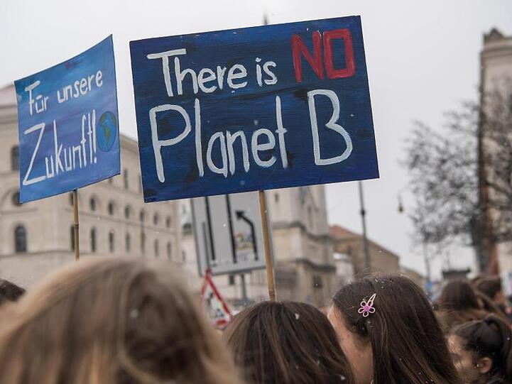 Schüler demonstrieren mit selbstgemalten Plakaten vor der Universität in München für den Klimaschutz. Foto: Peter Kneffel