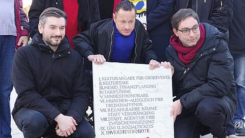Der Cellist Johannes K&ouml;nig, der Schauspieler Erwin Aljukić (Mitte) mit dem Linken-Stadtrat Stefan Jagel (rechts) mit den in Stein gemei&szlig;elten Forderungen im Kulturbereich am Marienplatz.