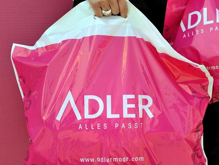 Plastiktüten der Textil-Einzelhandelskette Adler Modemärkte werden vor einer Filiale in Eching getragen. Foto: Frank Leonhardt/Archiv