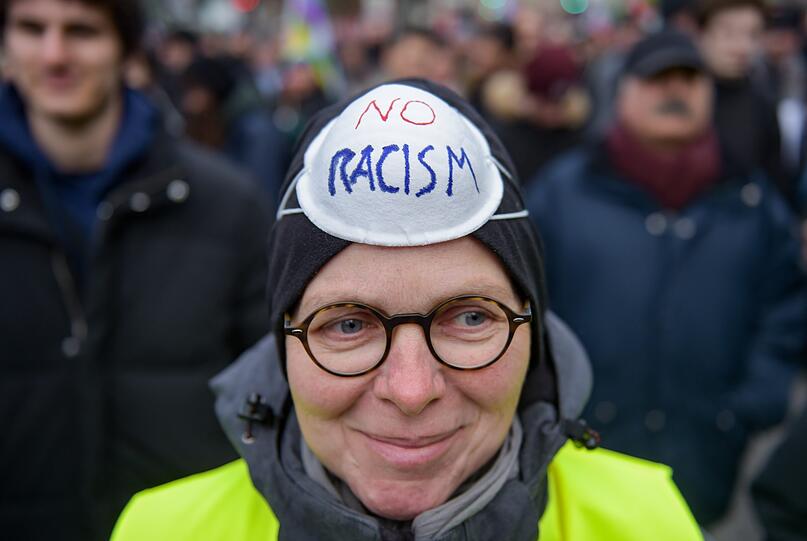 Eine Teilnehmerin einer Gegendemonstration zur Kundgebung "Merkel muss weg!" trägt eine Maske mit der Aufschrift "No Racism".