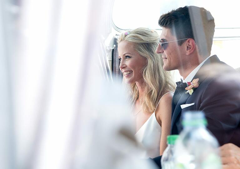 Mario und Carina: Er im dunkelblauen Anzug und mit Sonnenbrille. Sie in Weiß und Blumen im Haar.
