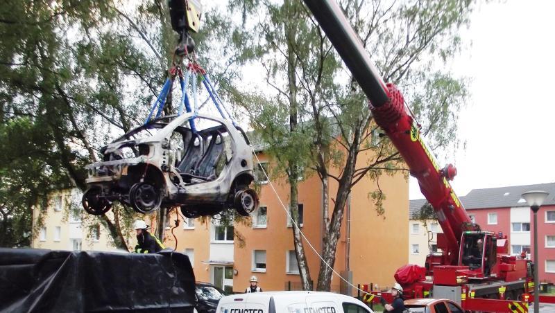 Ein Kranwagen der Dortmunder Feuerwehr hebt ein ausgebranntes E-Auto in einen Container. Ein Kranwagen der Dortmunder Feuerwehr hebt ein ausgebranntes E-Auto in einen Container.