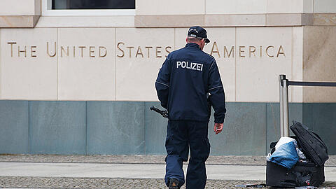 Ein Polizist begutachtet vor der US-Botschaft am Pariser Platz einen verdächtigen Koffer. Ein gewalttätiger Mann ist in Berlin festgenommen worden. Er hatte mit einem Bombenanschlag gedroht. Foto: Paul Zinken/Archiv