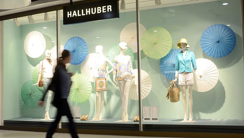 Eine Frau geht an einem Schaufenster des Modehauses Hallhuber vorbei.